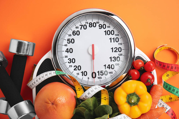 Flat lay composition with scales and healthy food on orange background - Photo, Image