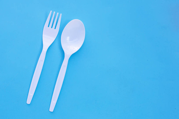 Plastic vork en lepel op blauwe ondergrond. - Foto, afbeelding