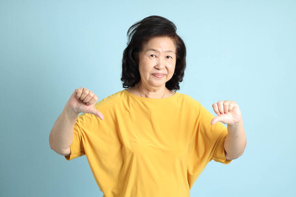 The senior Asian woman on the blue background. - Zdjęcie, obraz