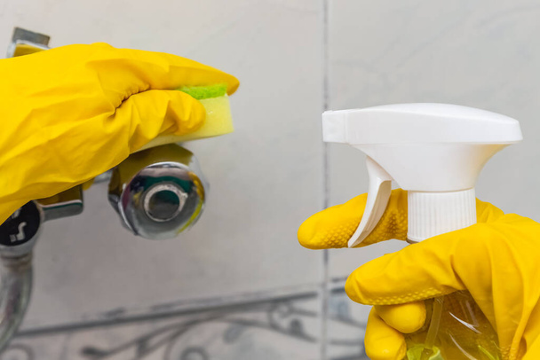 Using a sponge and a detergent while cleaning sink and tap in bathroom. - Valokuva, kuva