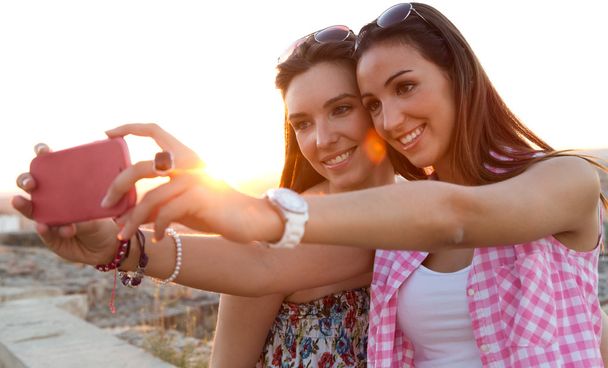 Beautiful girls taking a selfie on the roof at sunset. - Фото, зображення