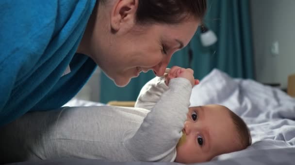 Jovem mãe dobra beijando as mãos do bebê filho sorrindo amplamente - Filmagem, Vídeo