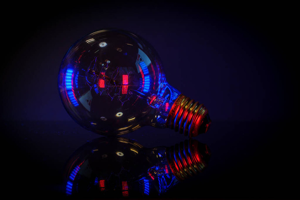 a light bulb is illuminated by colored lights - Foto, Imagen