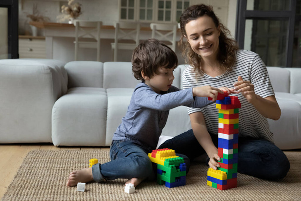 Gülümseyen anne ve küçük oğlu renkli inşaat oyuncaklarıyla oynuyor. - Fotoğraf, Görsel