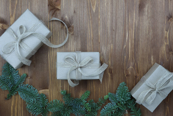 New Year's composition. Christmas gift made of kraft paper, pine cones, fir branches on a wooden background. Top view, flat lay, copy space. Zero Waste Concept. - Foto, afbeelding