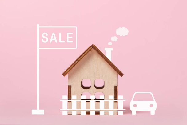 Будинок на продаж. Концепція купівлі та продажу нерухомості. Служба нерухомості. Купуйте дім. Маленький дерев'яний будинок на рожевому фоні.. - Фото, зображення