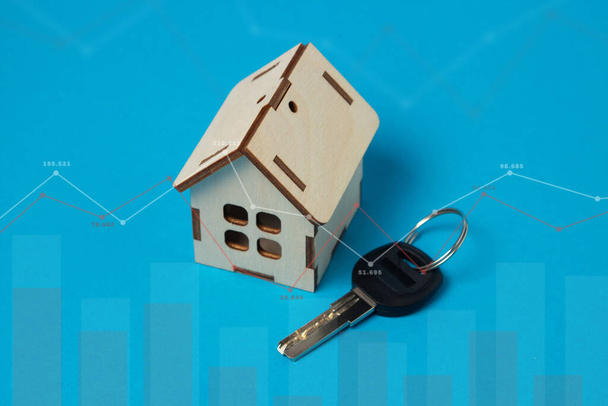 Zmiany cen nieruchomości. Koncepcja usług nieruchomościowych. Okazjonalny zakup domu. Mały drewniany domek na niebieskim tle - Zdjęcie, obraz