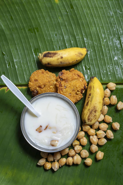 the traditional Onam Satya feast is served with fresh banana leaf vegetarian chickpea sundal, masala vada, bananas, appalam and milk payasam. - Photo, Image