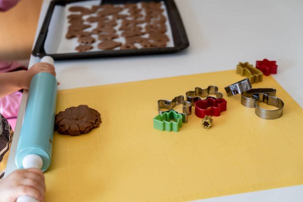 Selective focus. Child helping to making gingerbread cookies with various Christmas cookie cutters. Gingerbread dough. Family Christmas fun moments - Foto, imagen
