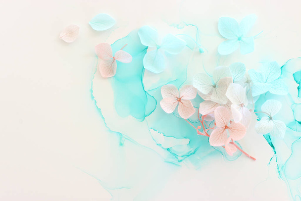 Creative image of pastel blue and pink Hydrangea flowers on artistic ink background. Top view with copy space - Foto, Imagem