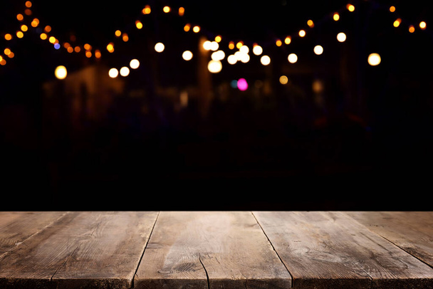 background Image of wooden table in front of abstract restaurant blurred lights - Photo, image
