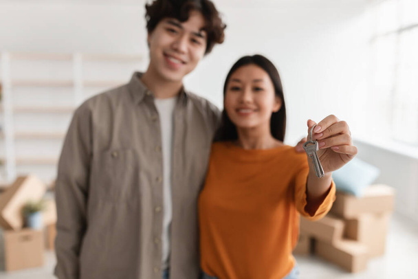 Happy Asian couple showing house key at camera, moving to their own apartment, selective focus - Photo, Image