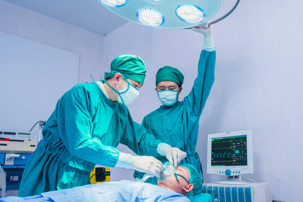 лікар-анестезіолог і носить кисневу маску для пацієнта в операційній, операційній або хірургічній кімнаті в лікарні для лікаря і пацієнта
 - Фото, зображення