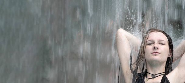 Ritratto di giovane donna punk alternativa ornata di dreadlocks, braccia sul collo, in Bikini nero sotto gli spruzzi d'acqua della cascata nella piscina Spa Wellness, copia lo spazio - Foto, immagini