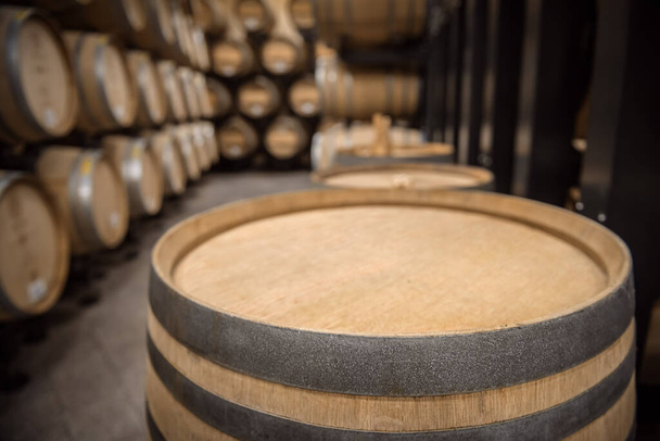 Parte superior del barril de vino de madera con espacio de copia en la parte superior frente al interior de la bóveda de bodega enfocada suave - Foto, Imagen