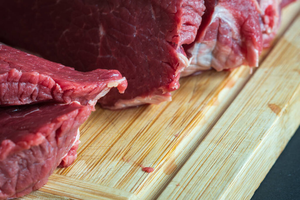 sliced raw roast beef meat on wooden cutting board closeup. - Zdjęcie, obraz