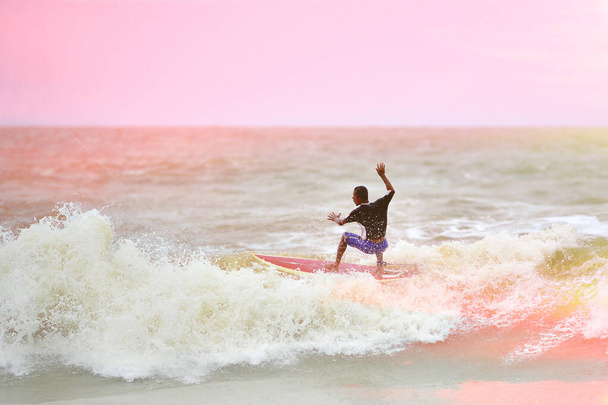 Sahilde sörf tahtası olan bir sörfçü. - Fotoğraf, Görsel