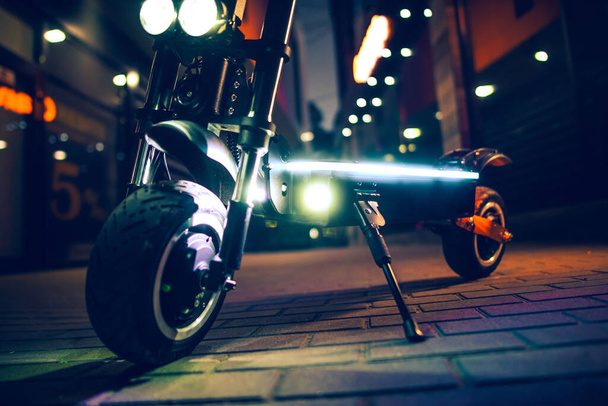 A close-up shot of an electric scooter at night with lights - Foto, Imagen