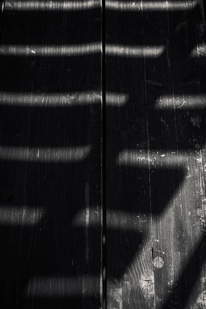 Un plano vertical de sombras sobre una superficie de madera en escala de grises - Foto, Imagen