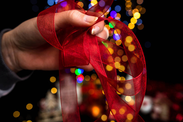 A man holding a decoration against bokeh Christmas lights - Foto, afbeelding