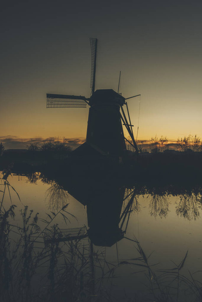A vertical shot of a traditional windmill in Kinderdijk, The Netherlands at sunset - Фото, зображення