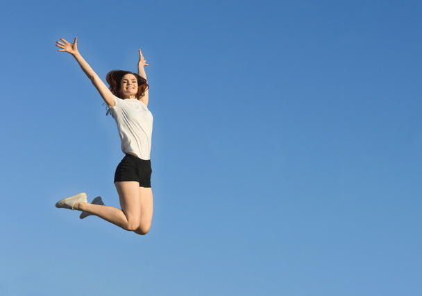 Slender woman jumping. Keep fit. Positive sport girl on background of blue sky. - Foto, Imagen