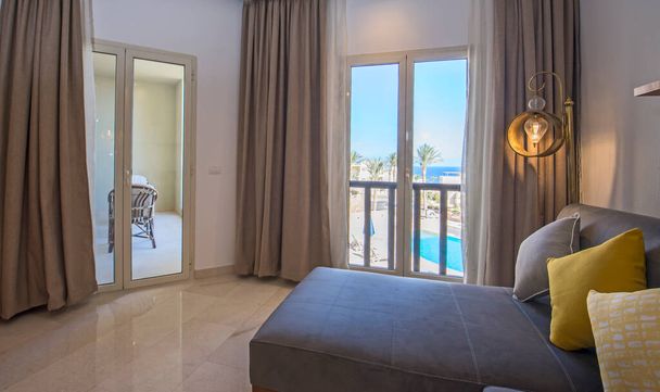 Salon salon w luksusowym apartamencie show home pokazujący wystrój wnętrz umeblowanie z balkonem taras i widok na morze - Zdjęcie, obraz
