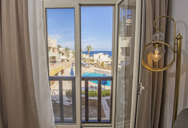 Meerblick aus dem Lounge-Fenster einer Luxuswohnung in der tropischen Badestadt  - Foto, Bild