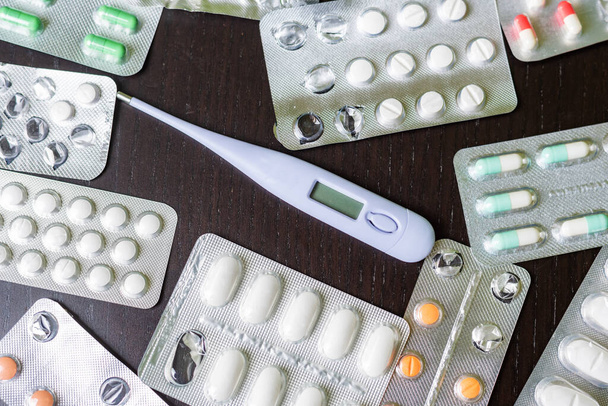 Several pills medicine tablets next to a thermometer. - Fotó, kép