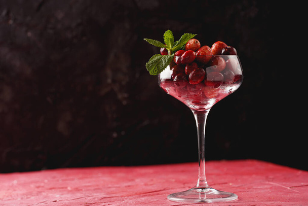Wide champagne glass filled with fresh raw cranberries on a round marble tray, copy space - Foto, imagen