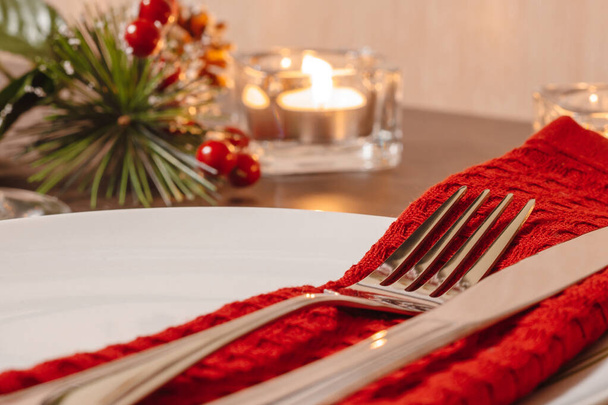 Mesa de Navidad. Placa y cubiertos en una servilleta. Preparación para la cena festiva. Velas ardiendo en la mesa en Nochebuena. - Foto, imagen