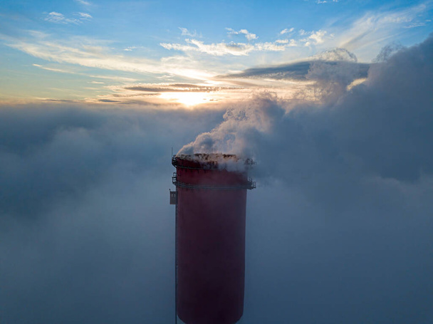 Chaminé alta de uma usina térmica acima do nevoeiro nos raios do pôr do sol. Vista aérea de drones. - Foto, Imagem