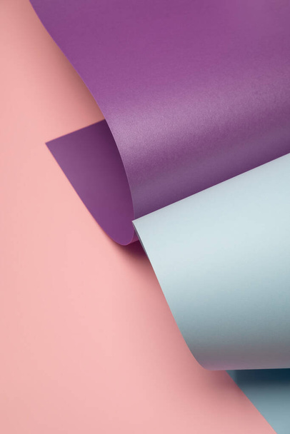 Pastel blauw en violet gerold papier op een licht roze achtergrond. Moderne minimale achtergrond - Foto, afbeelding