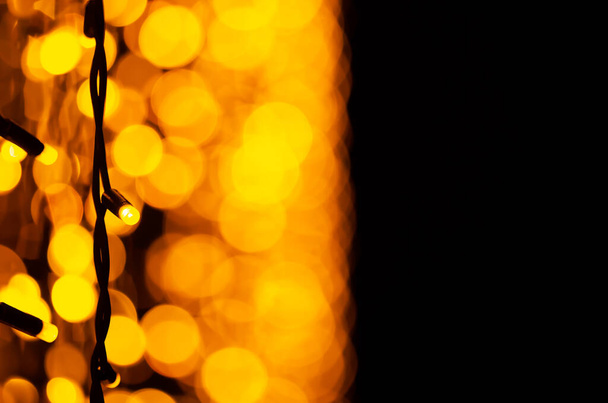 Abstrakter Hintergrund. Weihnachtsbeleuchtung auf der Stadtstraße. Neujahrsdekoration, selektiver Fokus. Girlanden auf der Straße. Festlicher dunkler verschwommener Hintergrund mit Bokeh-Licht. - Foto, Bild