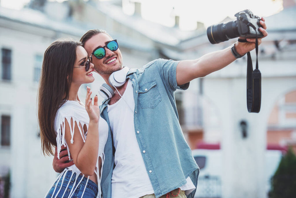 Joven feliz pareja están tomando foto selfie con cámara fotográfica
. - Foto, imagen