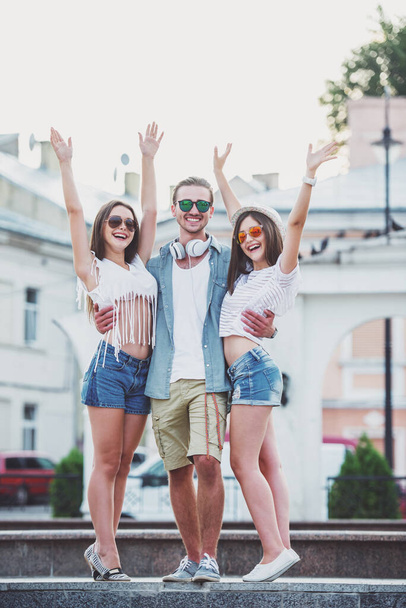 Friendship, leisure and people concept. Young people spend time together and posing and smiling into the camera, outdoors, in the town. - Φωτογραφία, εικόνα