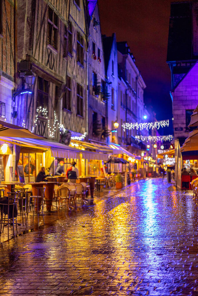 Place Plumereau - the square of medieval architecture built of half-timbered houses decorated of Christmas illuminations at the rain. Focused on the wet cobblestones in the foreground. Tours, France. - Fotó, kép