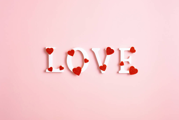 Aşk kelimesi pembe arka planda kırmızı kalplerle süslenmiş. Sevgililer Günün kutlu olsun. Düz yatış, üst görünüm - Fotoğraf, Görsel