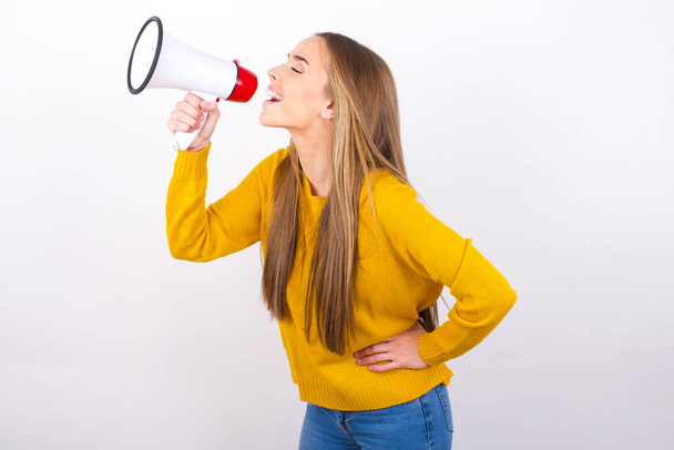 young woman shouting in megaphone, side view - Photo, Image