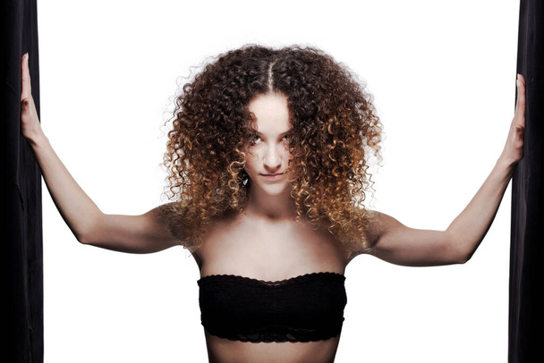 Beautiful brunette girl with long curly hair standing. Studio portrait with black stripes. - Fotó, kép