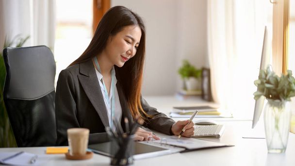 Una empresaria está haciendo un plan para su nuevo producto en su escritorio. una mujer de negocios asiática está trabajando en la oficina. - Foto, Imagen