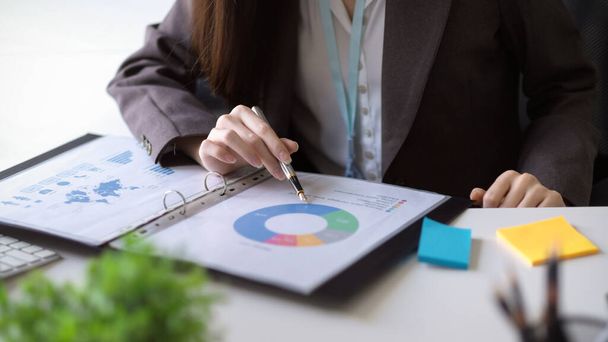 Bir kadın muhasebecinin ya da finans danışmanının yakın plan görüntüsü, iş yerindeki bir rapor dosyasındaki mali veri tablosunu analiz eder. - Fotoğraf, Görsel