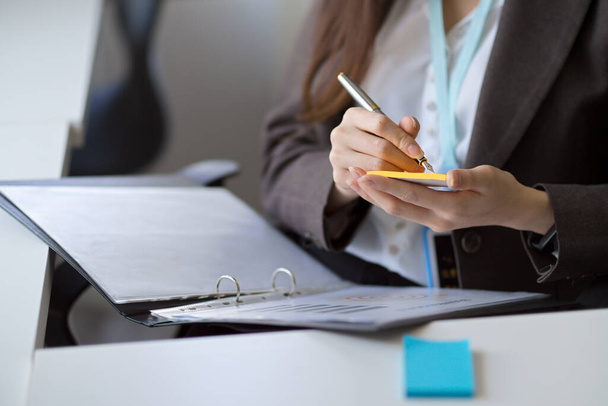 Image recadrée d'une femme d'affaires prenant des notes ou prenant des notes sur un bloc-notes papier à son bureau. - Photo, image