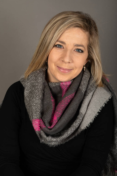 Portrait of a young  blond woman   looking to the camera in front of grey background    - Photo, image