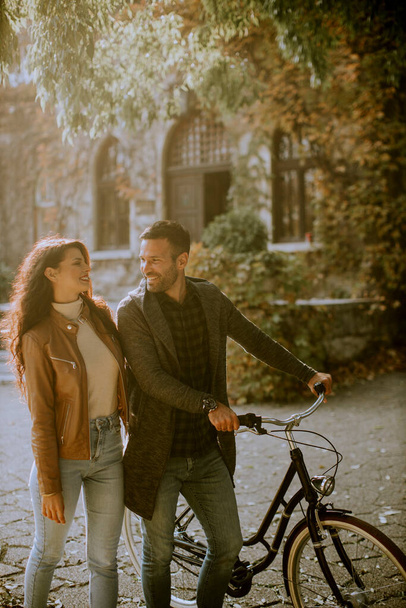 Bella giovane coppia a piedi con la bicicletta nel parco autunnale - Foto, immagini