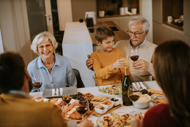 Familia feliz cenando con vino tinto en casa - Foto, Imagen