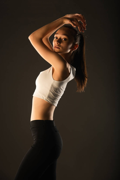 Portrait of beautful and attractive girl posing with her arms on her head in studio - Foto, imagen