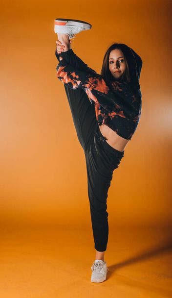 Fit young girl dancer performing a dance routine in the orange studio - 写真・画像