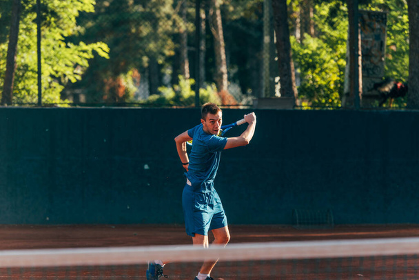 Professional equipped male tennis player beating hard the tennis ball with a backhand - 写真・画像