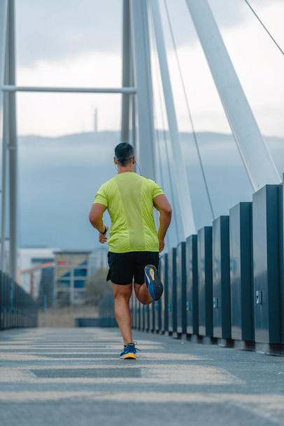 Зрілий м'язистий чоловік одягнений у спортивний одяг робить бігову вправу
 - Фото, зображення